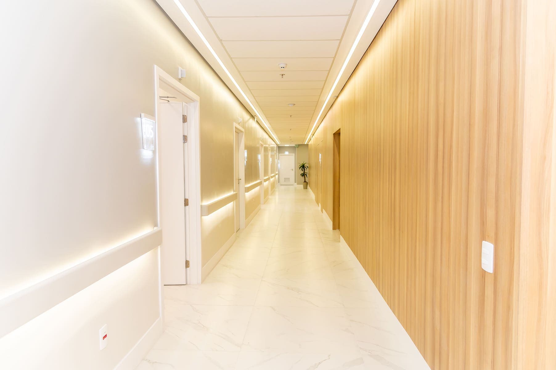 Corredor do One Day Hospital em Alphaville, com acabamento em madeira e iluminação indireta